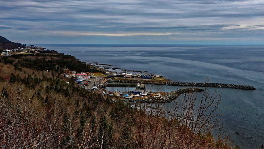 Une vue aérienne à couper le souffle de Sainte Anne des Monts, révélant la charmante ville côtière nichée entre les montagnes majestueuses et les eaux scintillantes du golfe du Saint-Laurent. La ville est entourée d'une verdure luxuriante, avec son architecture unique et sa communauté dynamique visible d'en haut.